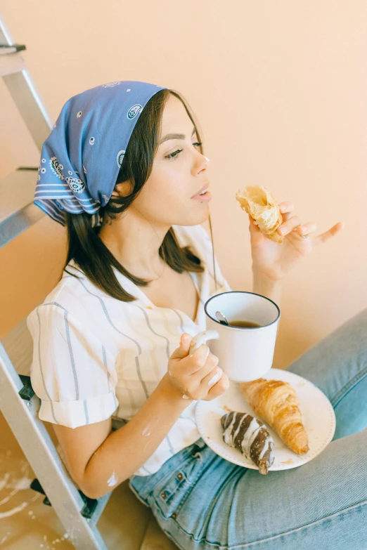 a woman sitting on the floor with a plate of food and a cup of coffee, eating garlic bread, profile image, gen z, eating cakes