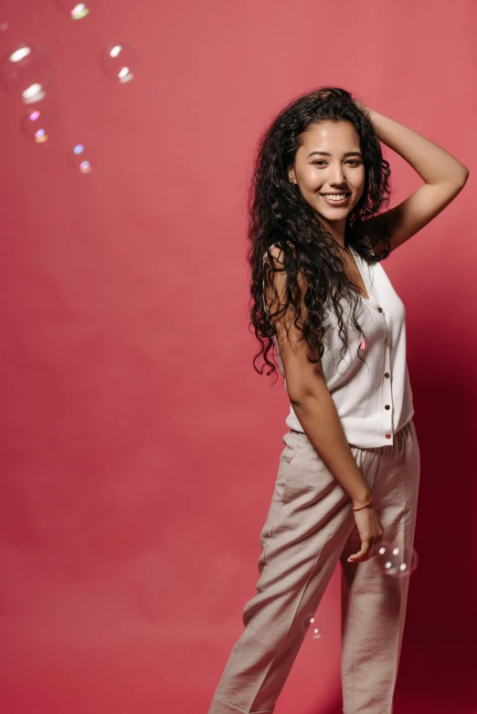 a young woman standing in front of a red background, trending on pexels, arabesque, wearing white pajamas, curls, alanis guillen, teenage girl