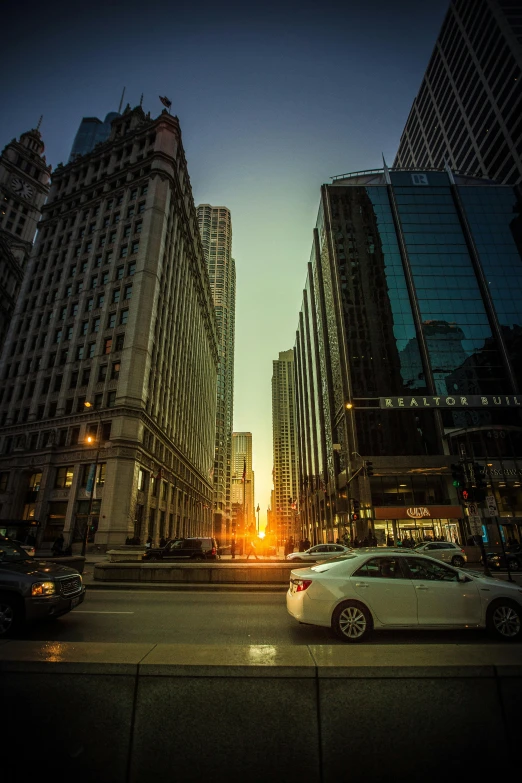 a white car driving down a street next to tall buildings, by Emanuel Witz, pexels contest winner, sun rising, chicago, square, tourist photo