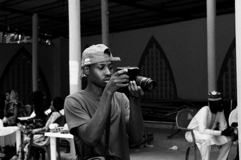 a black and white photo of a man holding a camera, by Chinwe Chukwuogo-Roy, 2 1 savage, 2 0 0 0's photo, tourist photo, working