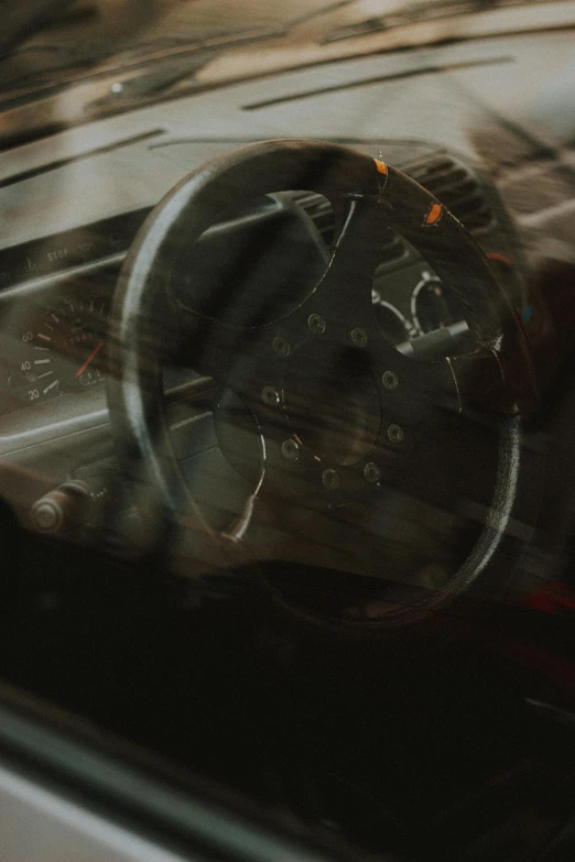 a close up of a steering wheel in a car, by Thomas Wijck, moody dim faint lighting, racing, looking left