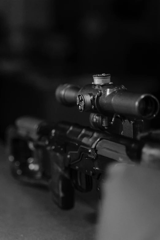 a close up of a rifle on a table, a black and white photo, unsplash, night vision, sharp focus »