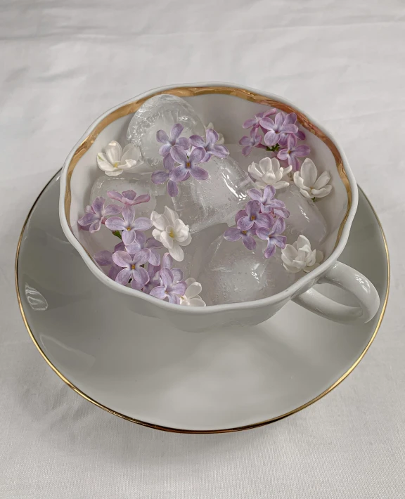 a close up of a cup of water with flowers in it, inspired by Wlodzimierz Tetmajer, entrapped in ice, lilac, gold flaked flowers, tabletop model