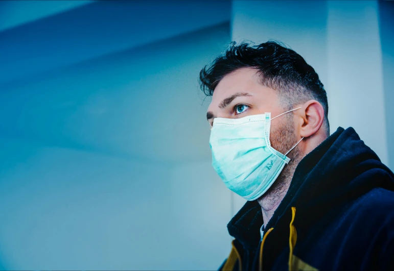 a close up of a person wearing a face mask, trending on pexels, hospital background, looking to his side, coloured photo, **cinematic