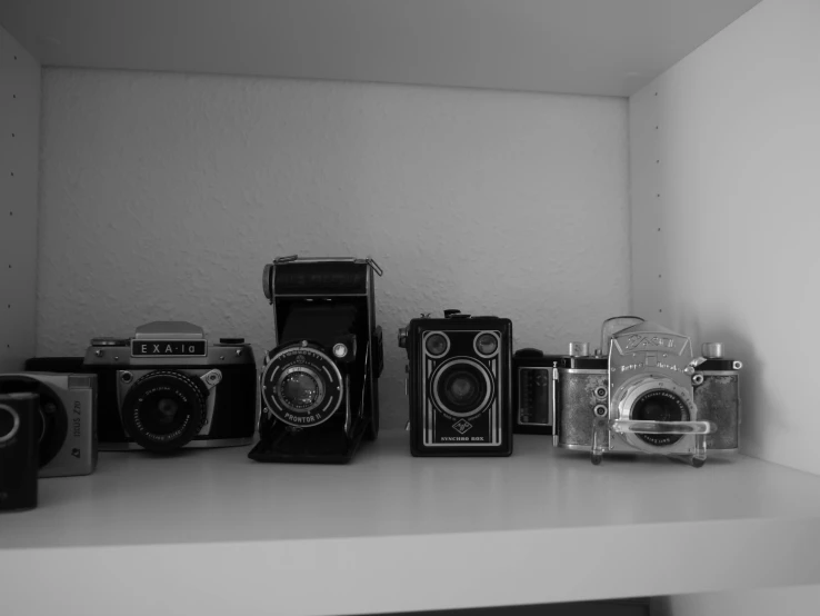 a couple of cameras sitting on top of a shelf, a black and white photo, in a row, medium format photography, photography], foto