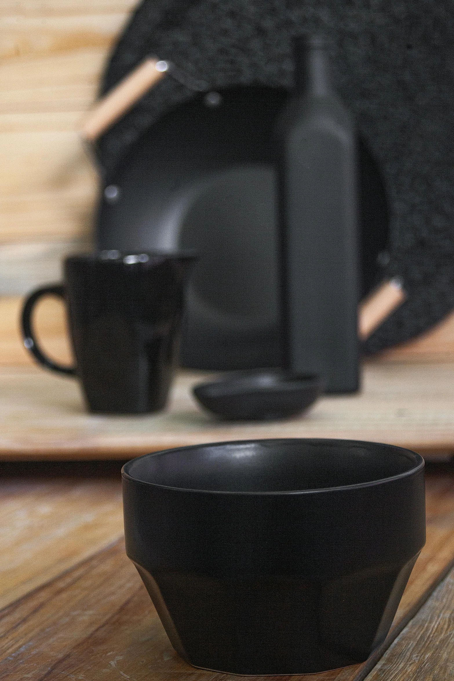 a black bowl sitting on top of a wooden table, inspired by Juan O'Gorman, bauhaus, matte black, two, place setting, hero shot