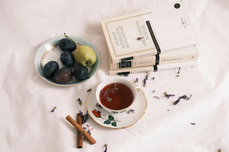 a book sitting on top of a table next to a cup of tea, a still life, inspired by Isabel Codrington, pexels contest winner, fruit and feathers, subtle purple accents, ingredients on the table, petite pear slim figure