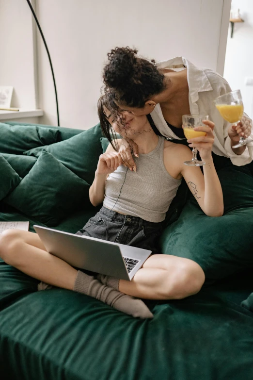 a man and woman sitting on a couch with a laptop, by Carey Morris, trending on pexels, happening, lesbian kiss, drinking champagne, couple on bed, 🍸🍋