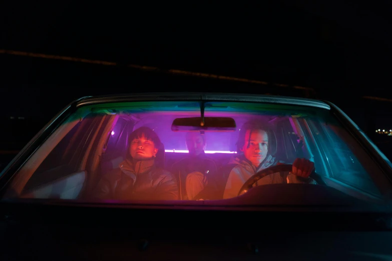 a couple of people that are sitting in a car, inspired by Nan Goldin, realism, neon purple light, stanger things, high quality photo, fargo