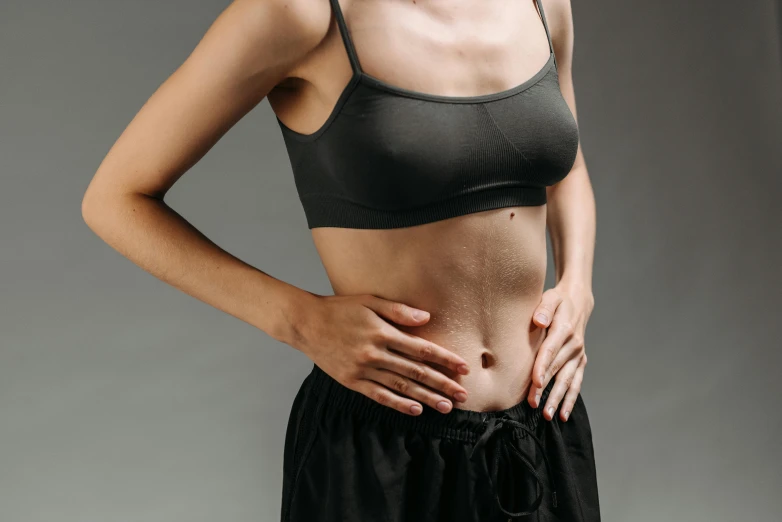 a woman standing with her hands on her hips, trending on pexels, inside a cavernous stomach, manuka, on a gray background, sweating