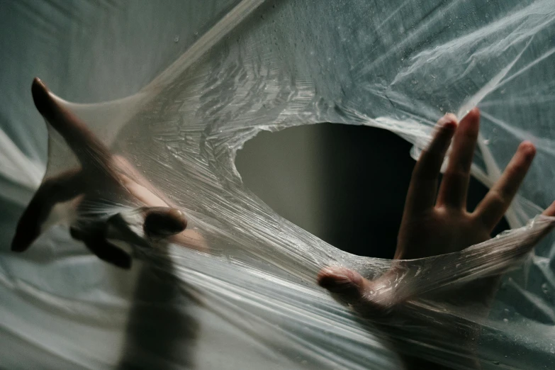 a close up of a person's hands wrapped in plastic, inspired by Elsa Bleda, pexels contest winner, marble hole, silk tarps hanging, portal opening, vinyl material