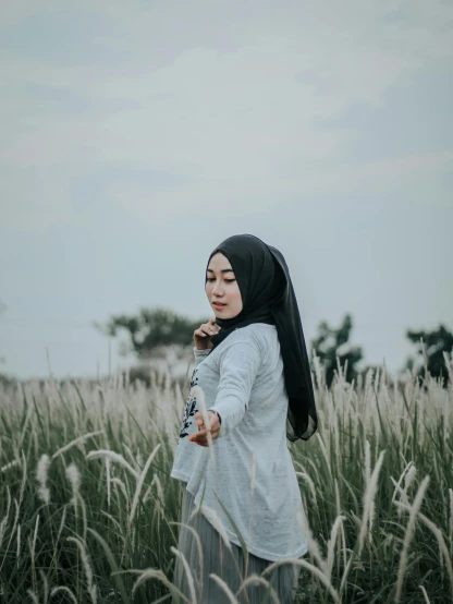 a woman standing in a field of tall grass, a picture, by Basuki Abdullah, unsplash, hurufiyya, 🤤 girl portrait, white and grey, switch, half body photo