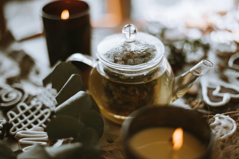 a tea pot sitting on top of a table next to a candle, trending on pexels, herbs, background image, floating candles, middle close up composition