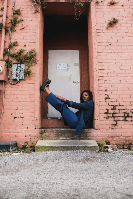 a woman sitting in the doorway of a building, an album cover, by Dulah Marie Evans, pexels contest winner, black arts movement, doing a kick, satisfied pose, stretching to walls, blues