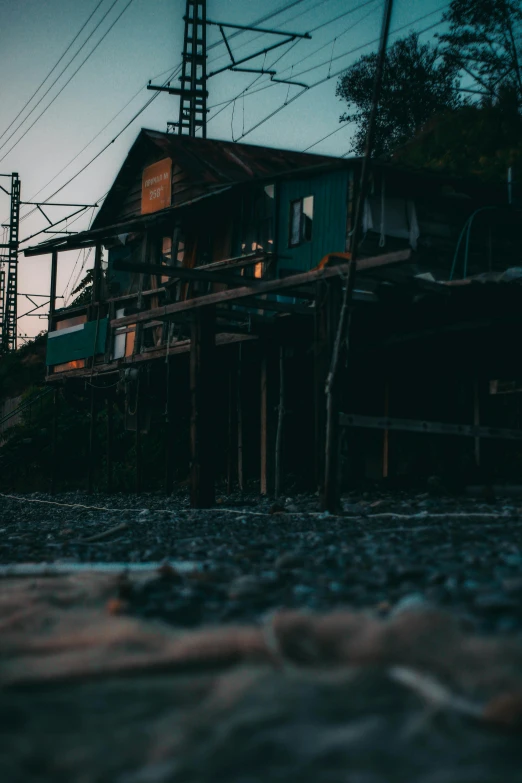 a house sitting on top of a beach next to a body of water, a picture, inspired by Elsa Bleda, unsplash, realism, twilight junkyard, standing in a township street, low - angle shot, shack close up