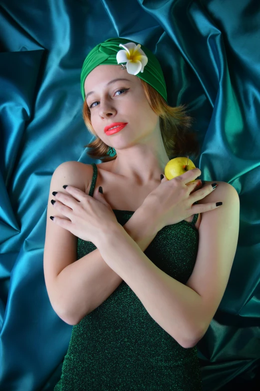 a woman in a green dress and a flower in her hair, an album cover, inspired by Tamara Lempicka, flickr, wearing a lemon, photography alexey kurylev, wearing teal beanie, on a velvet tablecloth