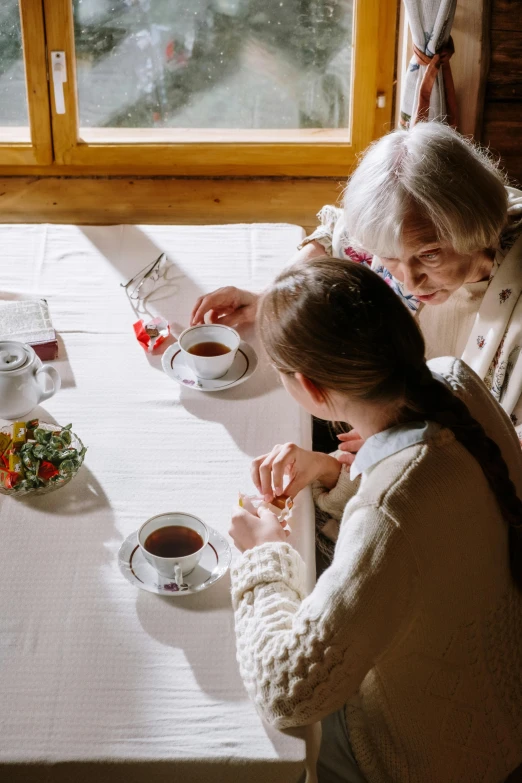 a group of people that are sitting at a table, a cross stitch, tea, the look of an elderly person, flatlay, private moment