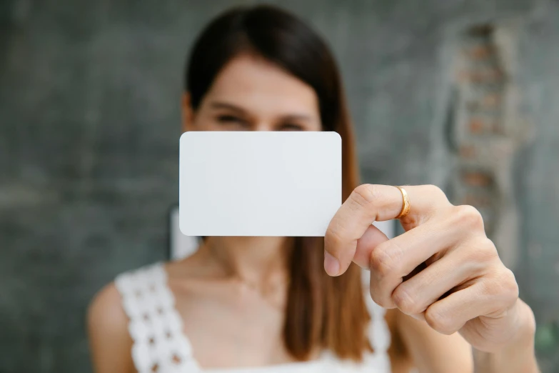 a woman holding a blank business card in front of her face, pexels contest winner, private press, white pearlescent, rounded corners, no - text no - logo, profile image