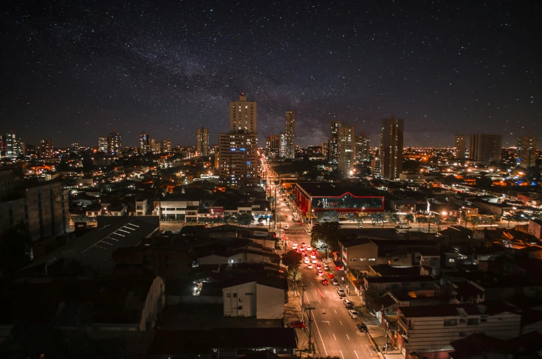 an aerial view of a city at night, by Alejandro Obregón, pexels contest winner, hyperrealism, carnaval de barranquilla, starry sky 8 k, ultrawide cinematic, city street view background