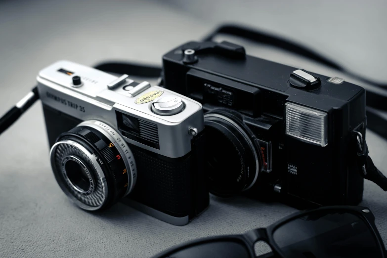 a camera sitting on top of a table next to a pair of sunglasses, a picture, unsplash, photorealism, yashica t 4, ((sharp focus)), ( ( dieter rams ) ), cameras lenses