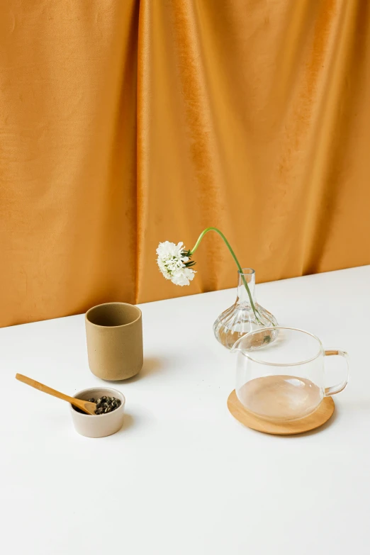 a white table topped with a vase filled with flowers, a still life, trending on unsplash, minimalism, moroccan tea set, brown clothes, modern studio light soft colour, brown and gold