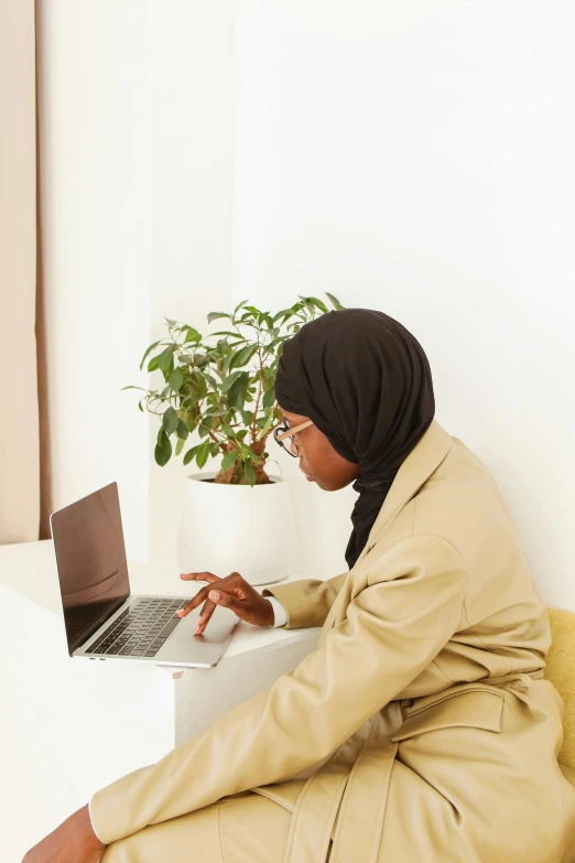 a woman sitting on a couch using a laptop, trending on pexels, hurufiyya, somali woman, plain background, professional profile picture, language