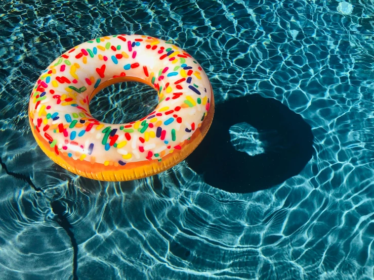 an inflatable donut floating in a pool, by Julia Pishtar, unsplash, cone shaped, summer lighting, fan favorite, profile image