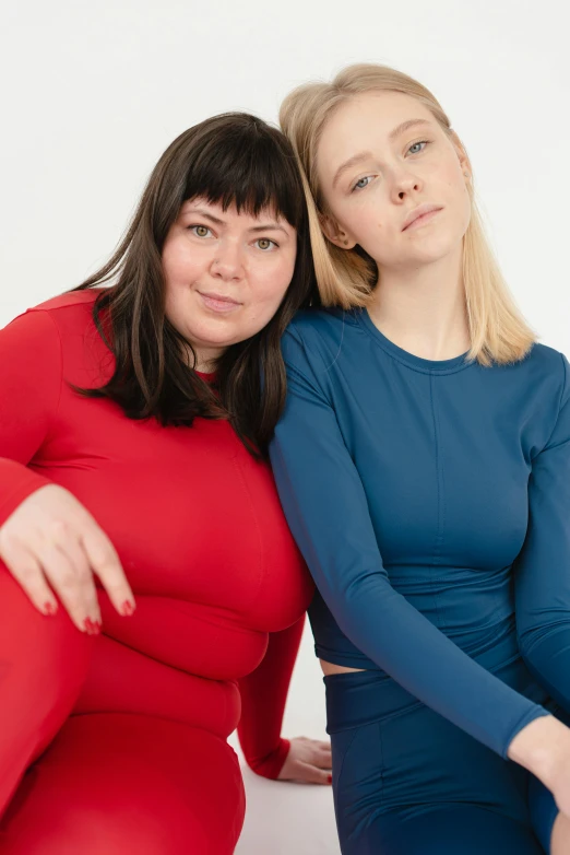 a couple of women sitting next to each other, an album cover, inspired by Louisa Matthíasdóttir, unsplash, red and blue garments, overweight, in spandex suit, eva elfie