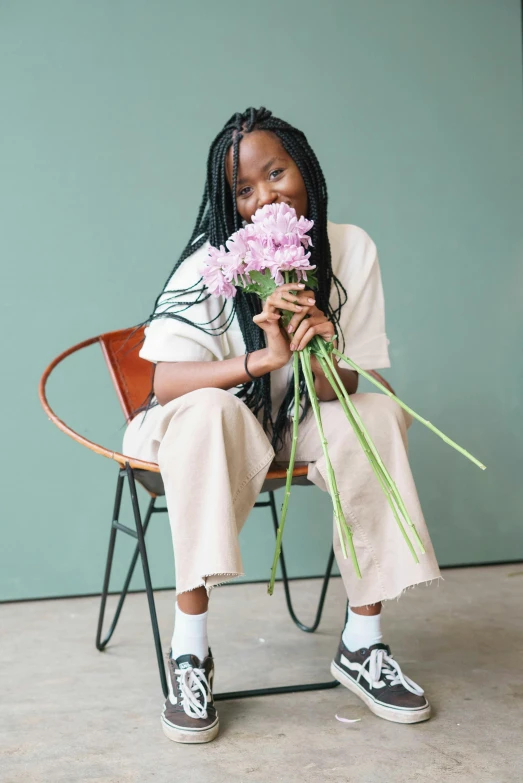 a woman sitting in a chair holding a bunch of flowers, by Dulah Marie Evans, trending on unsplash, visual art, box braids, wearing off - white style, longque chen, satisfied pose