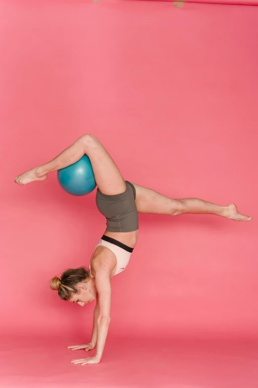 a woman doing a handstand with a blue ball, a colorized photo, pexels contest winner, arabesque, pink and teal, profile image, top down photo, curved body