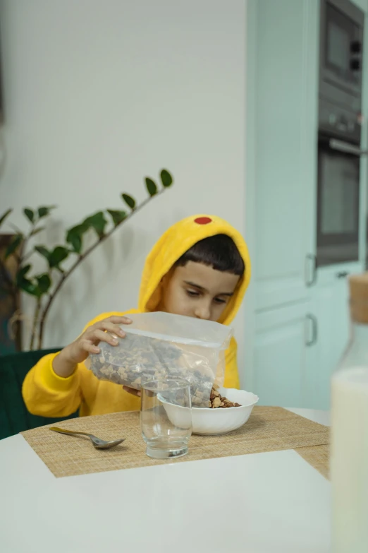 a little boy that is sitting at a table, wearing a yellow hoodie, cereal, thumbnail, petite