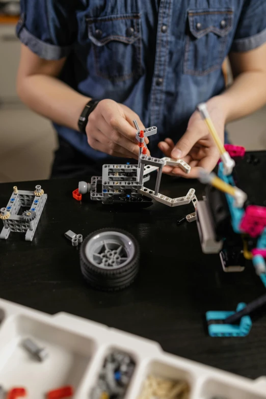a person working with legos on a table, pexels contest winner, les automatistes, mechanical features and neon, adafruit, built on a small, promo image
