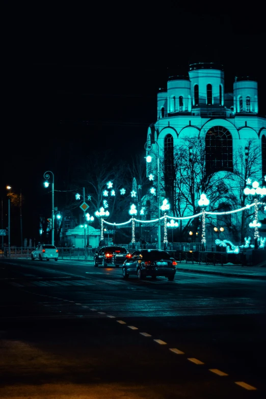 a car driving down a city street at night, by Adam Marczyński, pexels contest winner, baroque, russian temple, christmas lights, cold blue light, square