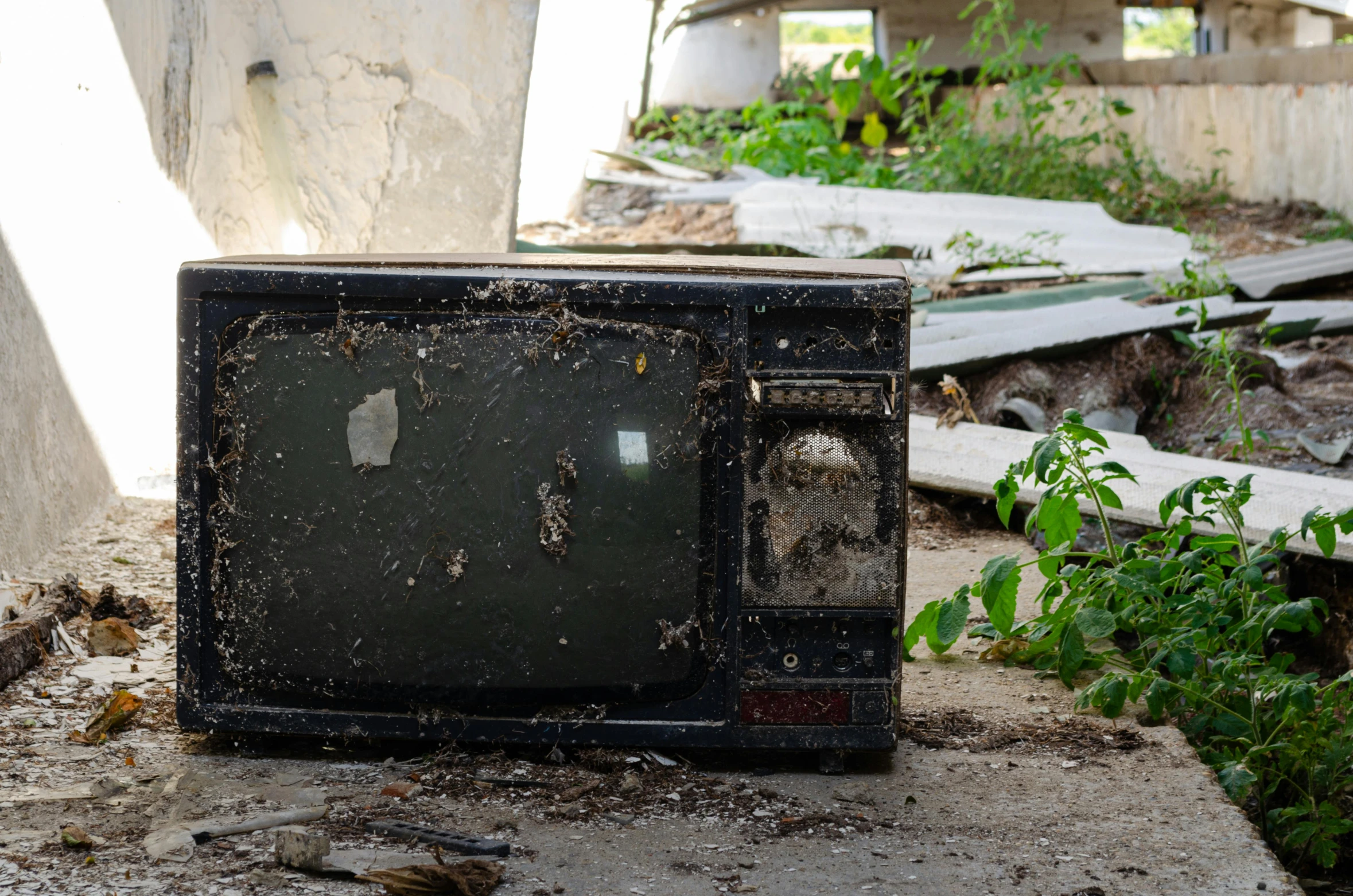 a black microwave sitting on top of a cement floor, unsplash, video art, overgrown spamp, tvs, in ruins, promo image