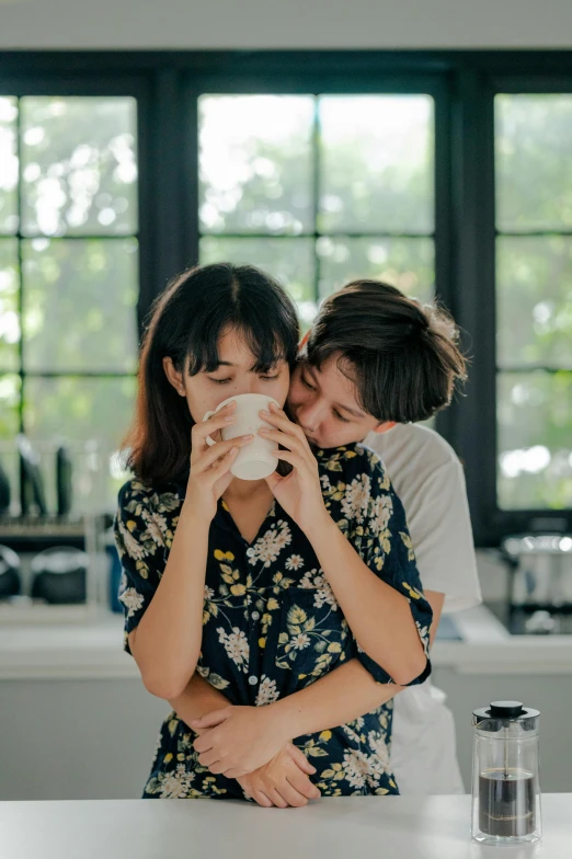 a couple of women standing next to each other in a kitchen, by Tan Ting-pho, trending on pexels, renaissance, kissing together cutely, coffee cup, yaoi, embrace