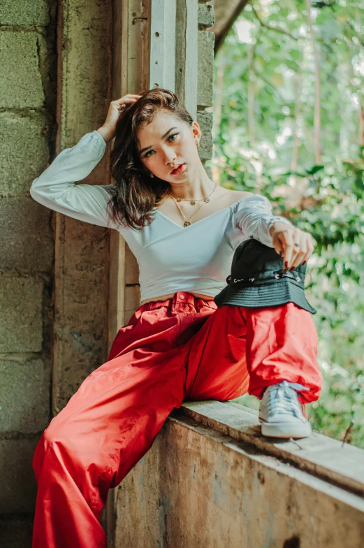 a woman sitting on top of a window sill, by Basuki Abdullah, trending on pexels, renaissance, red shirt brown pants, hailee steinfeld, clothed in ancient street wear, on wooden table