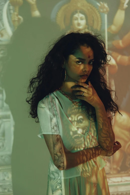 a woman standing in front of a painting, an album cover, inspired by Elsa Bleda, trending on pexels, hyperrealism, arms covered in gang tattoo, portrait of vanessa morgan, curls, james jean style