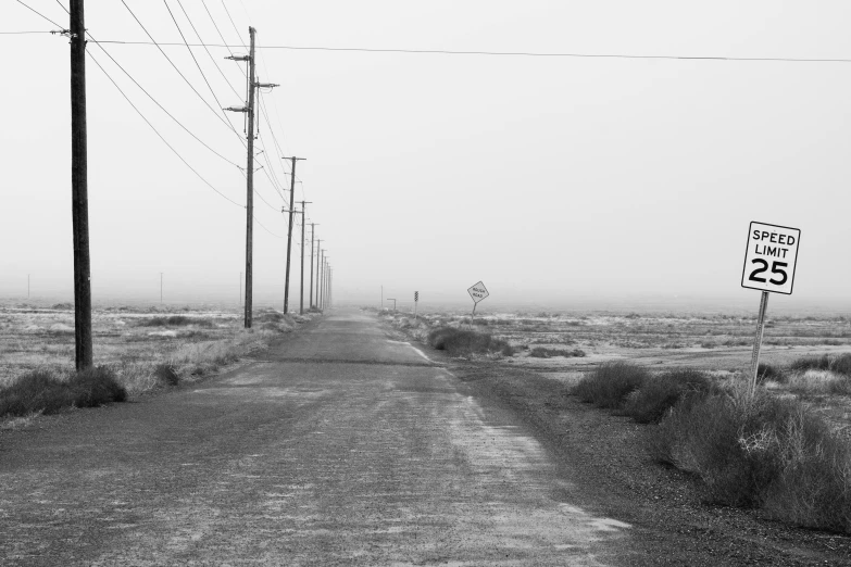 a black and white photo of a dirt road, a black and white photo, by Ryan Pancoast, postminimalism, misty ghost town, electric cables, central california, nuclear winter