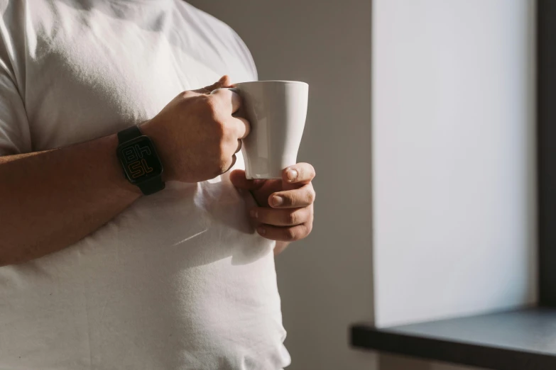 a close up of a person holding a cup, happening, man in white t - shirt, relaxed posture, wearing a watch, white mug