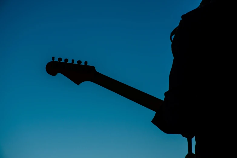 a silhouette of a person holding a guitar, an album cover, unsplash, clear blue sky, low detail, billboard image, modeled