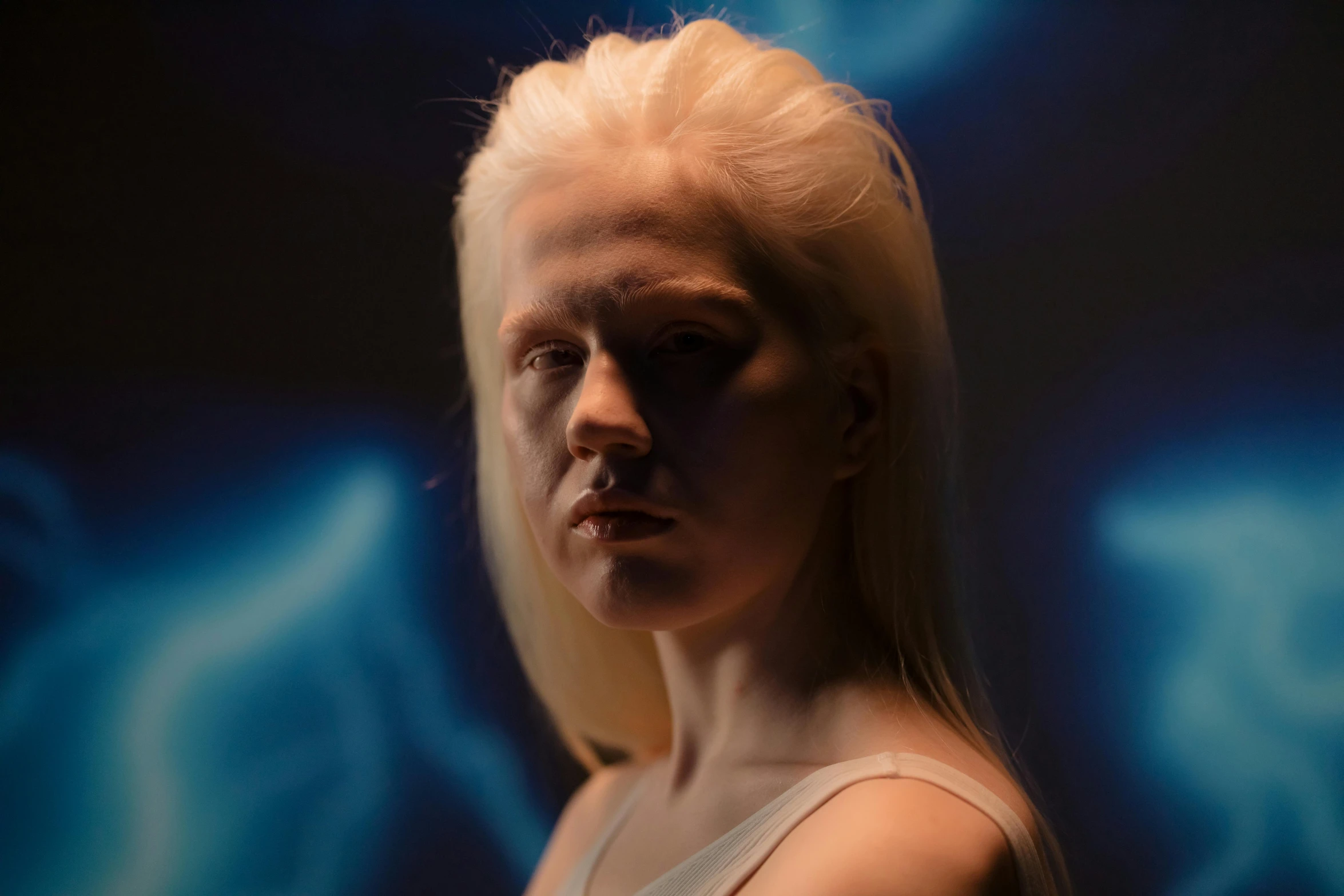a woman with blonde hair standing in front of a blue background, inspired by Elsa Bleda, featured on zbrush central, hyperrealism, intense albino, from a 2 0 1 9 sci fi 8 k movie, still from a music video, in front of a black background