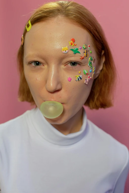 a woman with sprinkles on her face blowing a bubble, an album cover, inspired by Russell Dongjun Lu, trending on pexels, patricia piccinini, sadie sink, nonbinary model, silicone skin