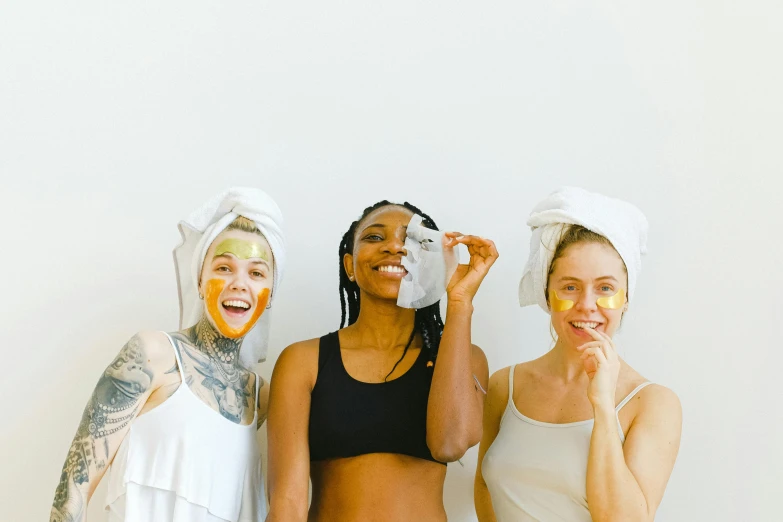 a group of three women standing next to each other, trending on pexels, renaissance, gold mask, wearing a towel, manuka, silicone skin