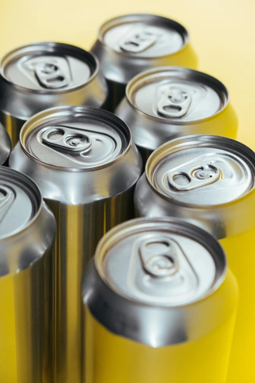 a group of aluminum cans stacked on top of each other, a digital rendering, unsplash, hyperrealism, yellow, drinks, silver, adult