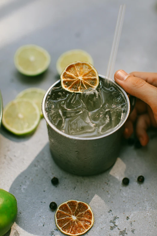 a close up of a person holding a drink in a cup, unsplash, renaissance, lime, tin can, silver small glasses, garnish