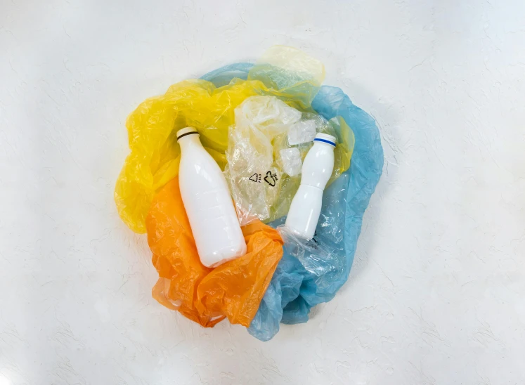 a plastic bag sitting on top of a sink filled with bottles, a marble sculpture, by Jessie Algie, unsplash, colored milk tea, yellow and blue, white and orange breastplate, 5k