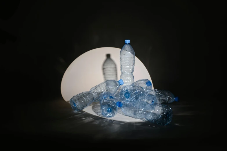 a white plate topped with plastic bottles of water, a still life, inspired by Anna Füssli, plasticien, volumetric lights, back lit lighting, lamp ( ( ( mirror ) ) ) ), dramatic white and blue lighting