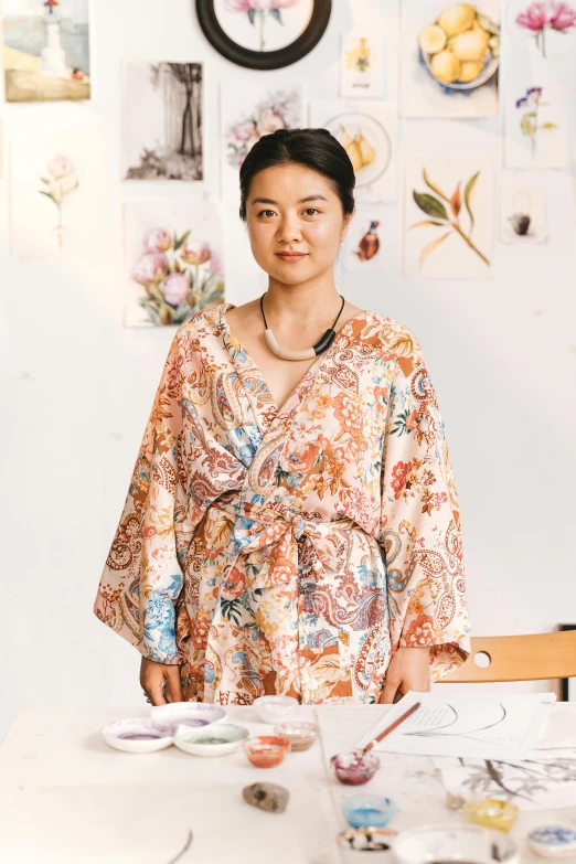 a woman that is standing in front of a table, by helen huang, process art, wearing a luxurious silk robe, portrait of a female art student, feng zhu |, may gibbs