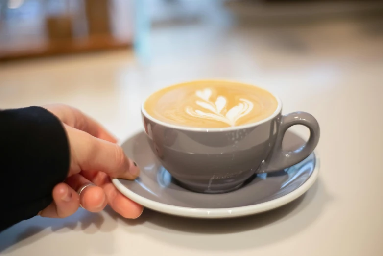 a close up of a person holding a cup of coffee, by Richmond Barthé, grey, creamy, item, cafe