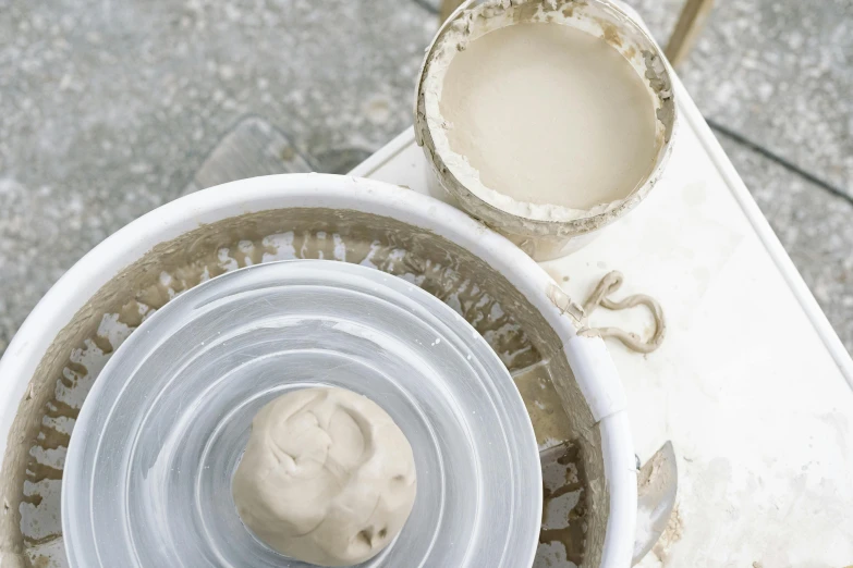 a white bowl sitting on top of a white table, a marble sculpture, inspired by Sarah Lucas, process art, mortar, thumbnail, pot, brown